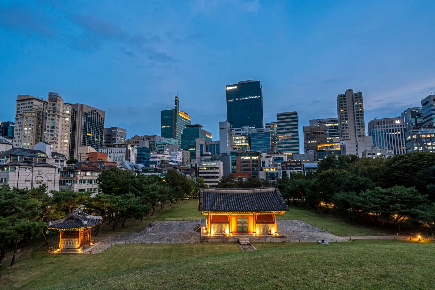 Jeongneung royal tomb at Seonjeongneung with Gangnam office towers at dusk
