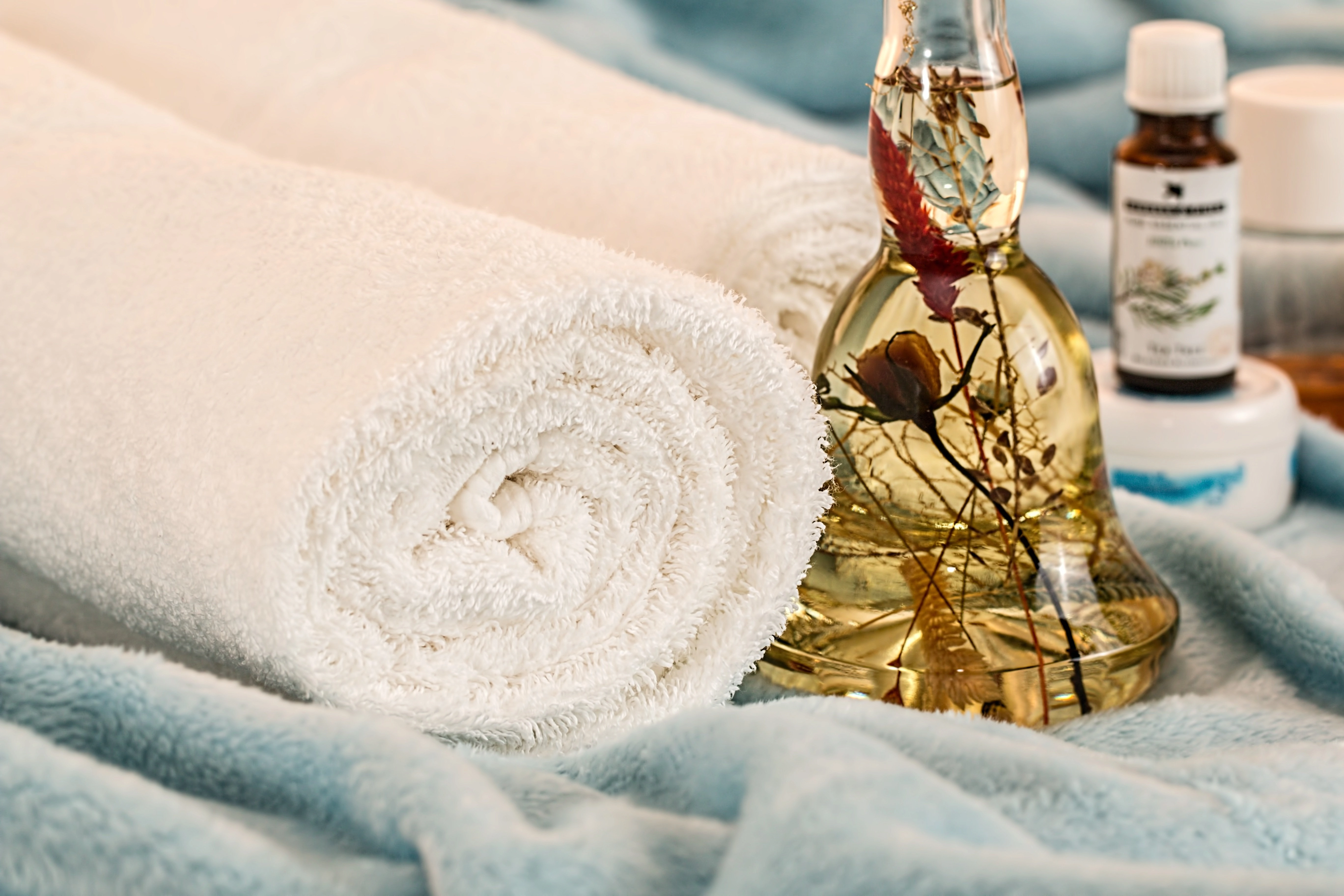 Rolled spa towel and botanical treatment oils prepared for a skincare service