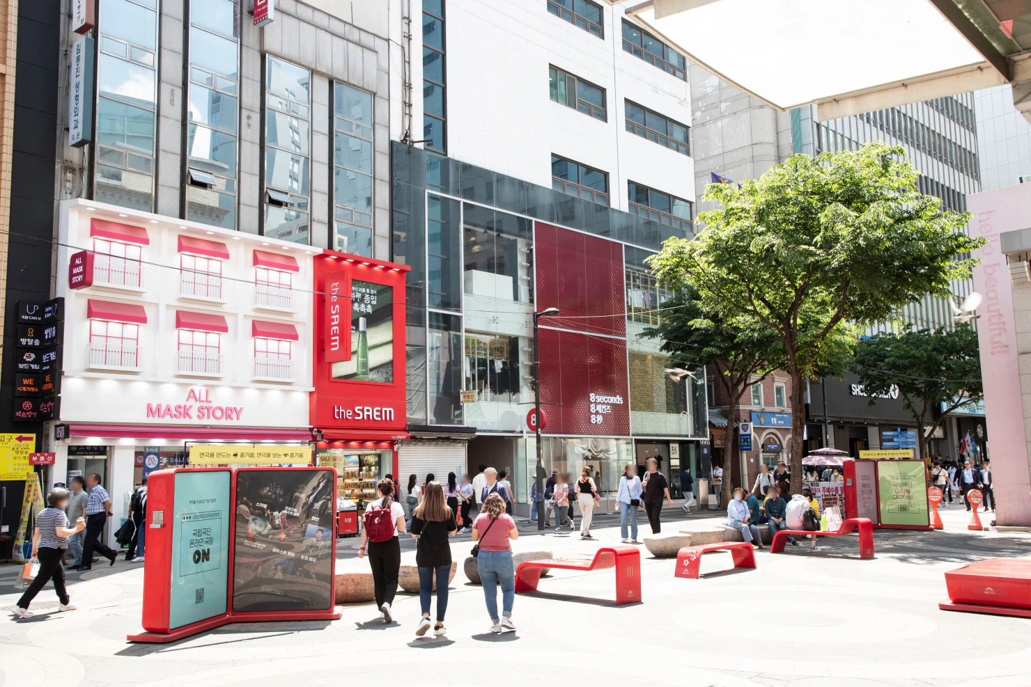 Pedestrians and red benches outside shops in Myeongdong, Seoul.